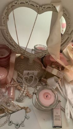 a table topped with jewelry and a heart shaped mirror