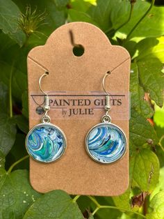 These one-of-a-kind earrings each have a unique design made from acrylic paint. The paint skin is placed in the earring bezel and then sealed with a glass cabochon. The beautiful designs are like wearing mini works of art! Each earring is approximately .75 inch across and 1 inch long.   Stainless steel wire hooks.  Earrings make wonderful gifts for any special person in your life, including yourself!! Please avoid swimming, bathing, or submerging it in water. Handmade. Free shipping. Artsy Blue Dangle Earrings, Artistic Turquoise Earrings With Ear Wire, Artsy Blue Nickel-free Jewelry, Artistic Hand Painted Blue Jewelry, Artsy Nickel-free Blue Jewelry, Unique Hand Painted Blue Earrings, Artsy Turquoise Nickel-free Earrings, Handmade Artistic Blue Earrings, Artsy Blue Earrings With Artistic Design