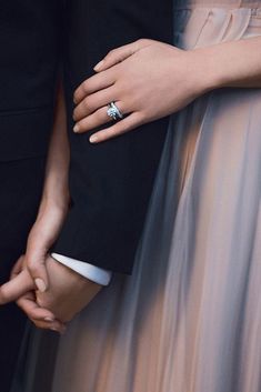 two people holding hands and wearing rings on their fingers, with one person's arm wrapped around the other