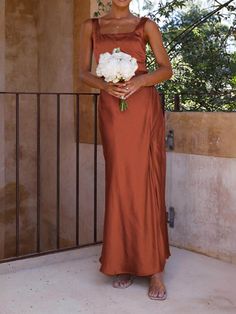 a woman in an orange dress holding a white flower and standing next to a balcony