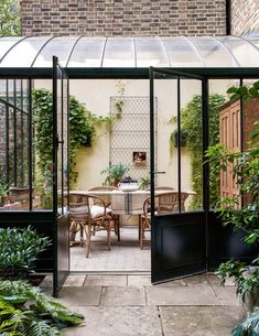 an enclosed patio with tables and chairs surrounded by greenery