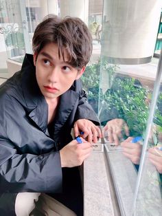 a young man is looking at his cell phone while sitting in front of a fish tank