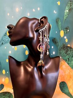 This enchanting mermaid moon ear cuff is sure to make a statement and bring out your inner magic! Silver ear cuff is embellished with a charm of two women in the moon, rainbow mermaid tail charm, iridescent drop crystals, seashell and starfish, and electroplated lava stone beads all dangling from silver and rainbow chains. This ear cuff is perfect for adorning pierced and non-pierced ears, and is lightweight and comfortable to wear. Lava Stone offers the following positive energies for the weare Silver Bohemian Cartilage Earrings For Party, Fantasy Style Single Earring For Festival, Bohemian Style Pierced Ear Cuff For Party, Bohemian Pierced Ear Cuff For Party, Celestial Single Earring For Party, Unique Pierced Dangle Ear Cuff, Bohemian Moon Charm Jewelry For Party, Whimsical Moon Charm Dangle Jewelry, Whimsical Dangle Moon Charm Jewelry