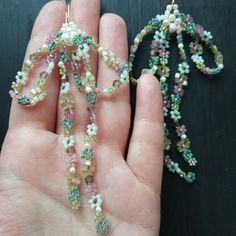 a hand holding a beaded necklace in it's left hand next to a string of beads