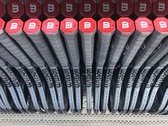 rows of red and black baseball bats sitting on top of each other