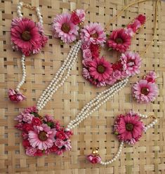 pink flowers and pearls are arranged on a wicker surface