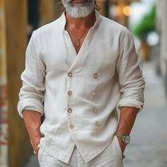 a man with a beard and white shirt is walking down the street in front of a building