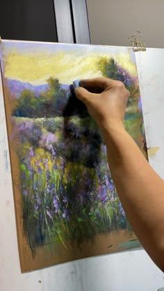 a person is painting flowers on an easel with a paintbrush in their hand