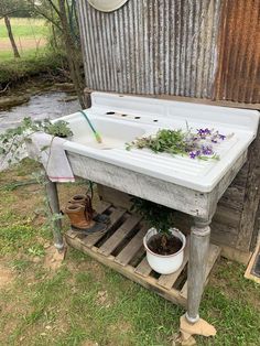 an old sink with plants growing out of it in front of a wooden wall and fence