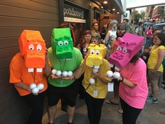 several people in costumes are holding eggs and wearing paper bags as they stand on the sidewalk