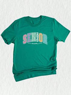 a green t - shirt with the word senior on it, sitting against a white background