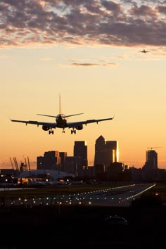 an airplane is flying over the city at sunset