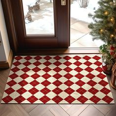 a red and white checkered door mat next to a christmas tree in front of a window