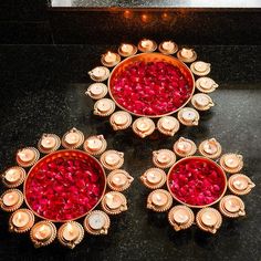 three red and gold decorated candles on a black counter top with lights in the middle