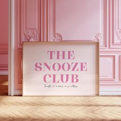 the snooze club sign in front of pink walls and wood flooring