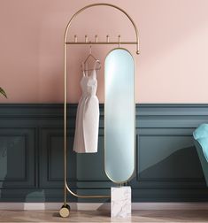 a dress hanging on a clothes rack next to a mirror and chair in a room with pink walls