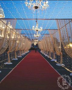 a red carpeted aisle with white drapes and chandeliers