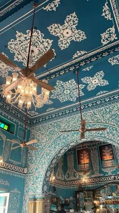 an ornately decorated ceiling with chandeliers and lights in a blue dining room