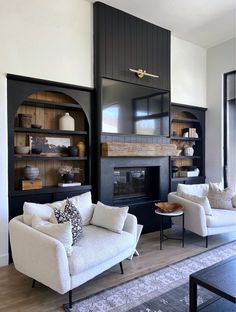 a living room with two white couches and a fire place in the middle of it