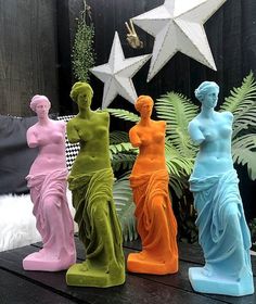 four colorful statues sitting on top of a wooden table next to a star shaped planter