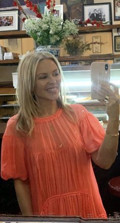 a woman taking a selfie with her cell phone in front of a bakery counter