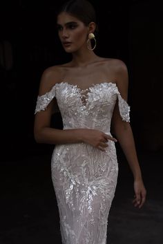 a woman in a white wedding dress with off the shoulder sleeves and an open back