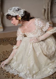 a woman in a wedding dress kneeling on the floor with her hand on her knee