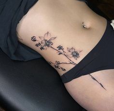 a woman's stomach with flowers on it and an arrow in the side tattoo