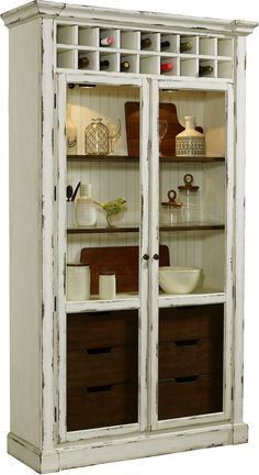 an old white china cabinet with glass doors and drawers on the bottom shelf is filled with items