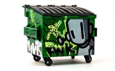 a green trash can with graffiti on it's side and black wheels, sitting in front of a white background