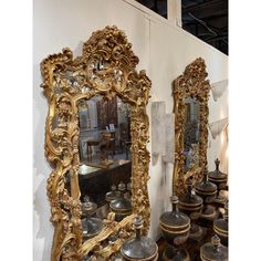 two large mirrors sitting next to each other in front of a wall filled with vases