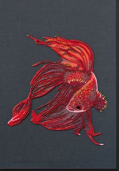 a red fish on a black background is featured in this embroidery pattern, which has been stitched onto the fabric