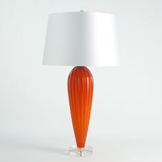 an orange glass lamp with a white shade on the base and a white fabric lampshade