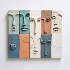 a group of different colored faces on a white wall