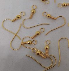 several pairs of gold - plated metal hooks and earwires are laid out on a white surface