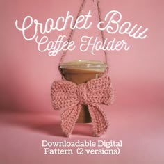 the crochet bow coffee holder is hanging from a hook on a pink background