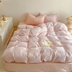 a bed with pink comforter and pillows in a white room next to two nightstands