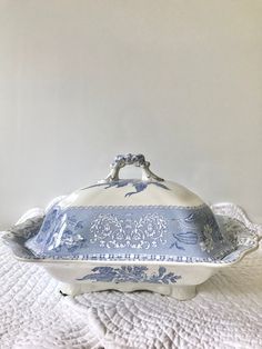 a blue and white covered dish sitting on top of a bed