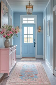 a hallway with blue walls, pink furniture and flowers in vases on the end table