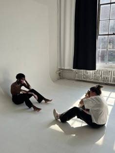 two people sitting on the floor in front of a window