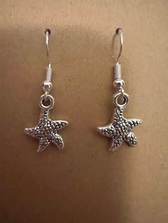 Silver starfish earrings on silver hypoallergenic nickel free fishhook earrings Casual Star Jewelry For Summer, Casual Star-shaped Summer Jewelry, Casual Summer Star Shaped Jewelry, Summer Starfish Charm Dangle Earrings, Summer Dangle Earrings With Starfish Charm, Summer Starfish Charm Drop Earrings, Silver Starfish Earrings For Summer, Silver Star Earrings For Summer, Nickel-free Silver Starfish Earrings