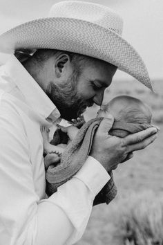 a man holding a baby in his arms while wearing a straw hat and white shirt