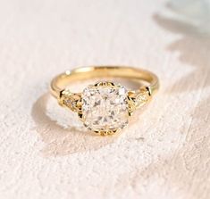 a yellow gold engagement ring with an old - cut diamond in the center on a white background