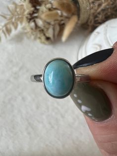 The Larimar ring in stainless steel, adjustable in size, is a piece of jewelry that carries the beauty of the Caribbean Sea. The ring's adjustable size allows it to be customized to fit different finger sizes, providing a comfortable and flexible wearing experience. The soft color of the Larimar is reminiscent of clear oceans and brings a calming and refreshing energy. Larimar is often associated with peace, calm and relaxation. Wearing this ring could therefore not only be fashionable but also serve as a symbol of serenity and inner balance. This Larimar ring, which is also size-adjustable, is not only a stylish accessory, but also an expression of natural beauty and relaxed elegance. Relaxed Elegance, Inner Balance, Larimar Ring, Larimar Rings, Caribbean Sea, Stylish Accessories, Rings Statement, Soft Colors, The Caribbean