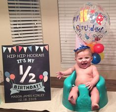 a baby sitting in a potty with balloons and a birthday sign