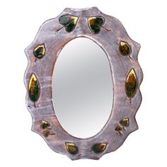 an oval mirror with leaves on it