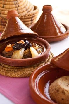 some brown bowls filled with food on top of a pink table cloth and wicker baskets