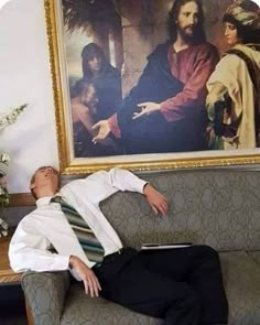 a man laying on top of a couch in front of a painting