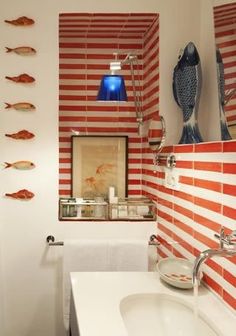 a bathroom with red and white striped wallpaper next to a bathtub filled with fish