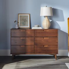 a wooden dresser sitting next to a lamp on top of a hard wood floor in a room